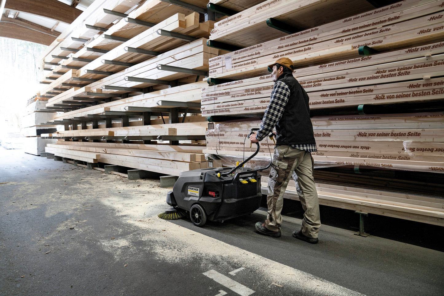 Karcher® KM 85/50 W Bp Walk-Behind Sweeper in use in lumber yard sweeping